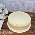Plain round anniversary cake on a wooden table.