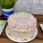 Pink whipped cream cake on a wooden table.