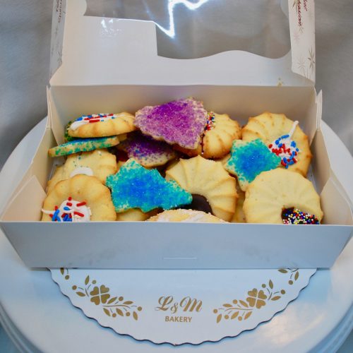 Assorted cookies in a white box on a white display board.