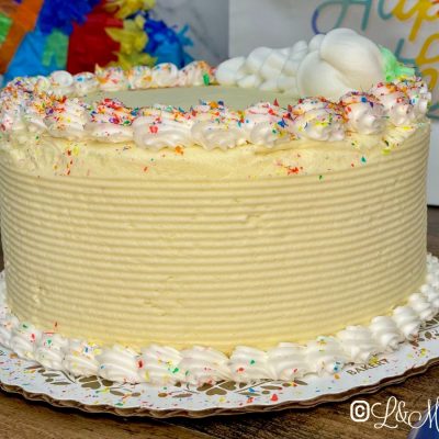 Seven inch round colorful cake on a white display board.