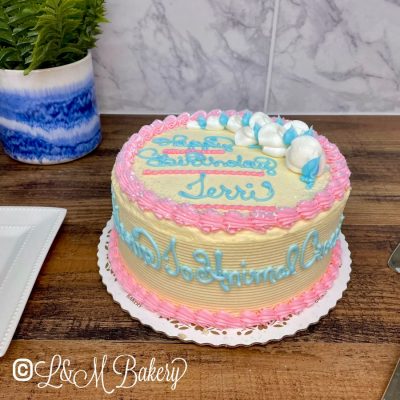 Seven inch pink and blue cake with writing on the side.