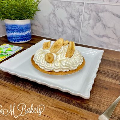 Banana whipped cream pie on a white serving tray.
