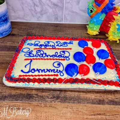 Blue and red birthday cake with balloons on wooden table.