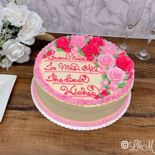 Pink bridal shower cake on a wooden table.