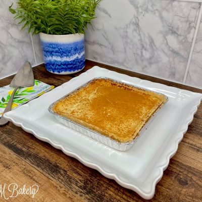 Tin pan of cheesecake on a white serving tray.