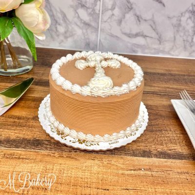 Chocolate buttercream communion cake on a wooden table.