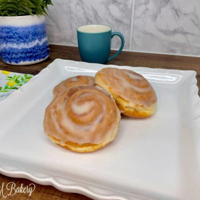 Cinnamon bun with glaze on a white serving tray.