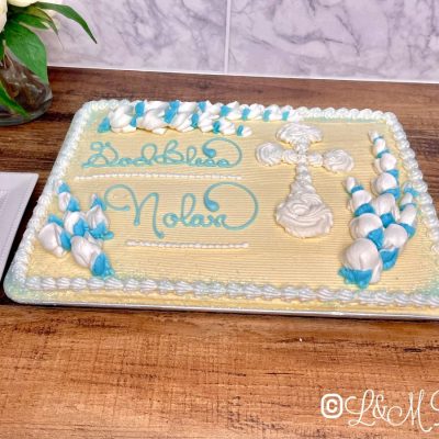 Blue and white communion cake on a wooden table.