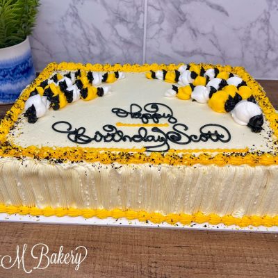 Black and yellow buttercream cake on a wooden table.