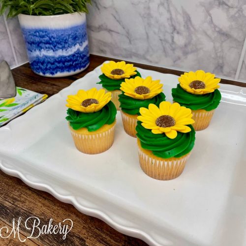 Yellow flower cupcakes on a white serving tray.