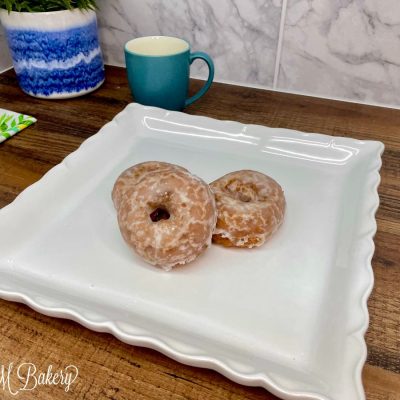 Glazed cruller on a white serving tray.