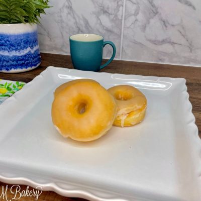 Glazed ring donut on a white serving tray.