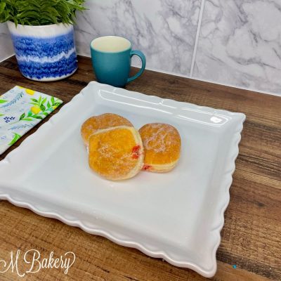 Jelly donut with sugar on a white serving tray.