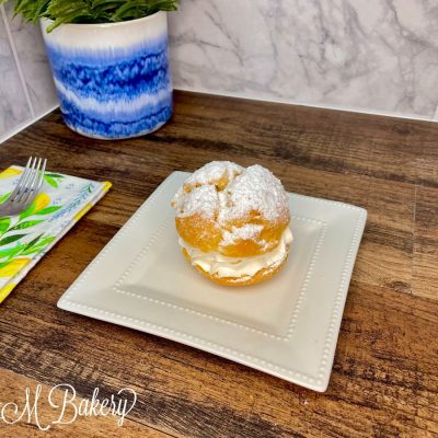 Large cream puff on a white serving tray.