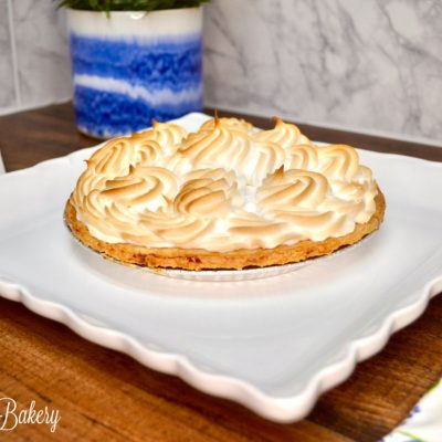 Lemon meringue pie on a white serving tray.