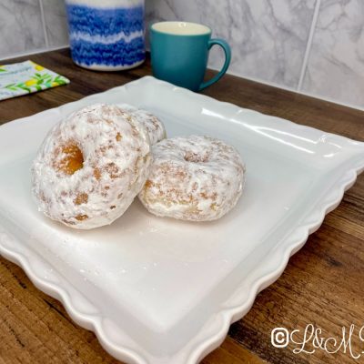Powdered ring donut on a white serving tray.