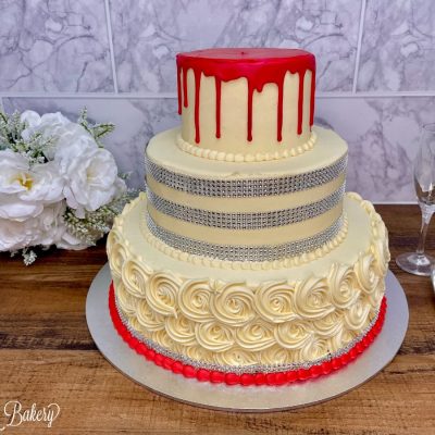 Red drip wedding cake on a wooden table.