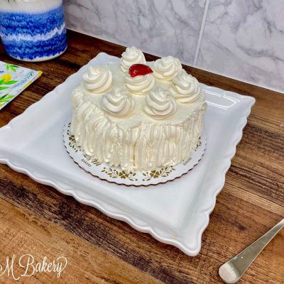Strawberry whipped cream cake on a white plate.