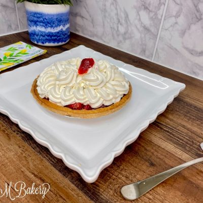 Strawberry whipped cream pie on a white serving plate.