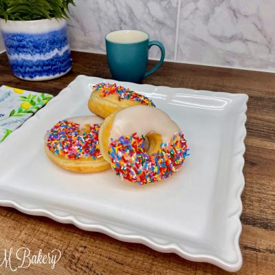 Vanilla ring with sprinkles on a white serving tray.